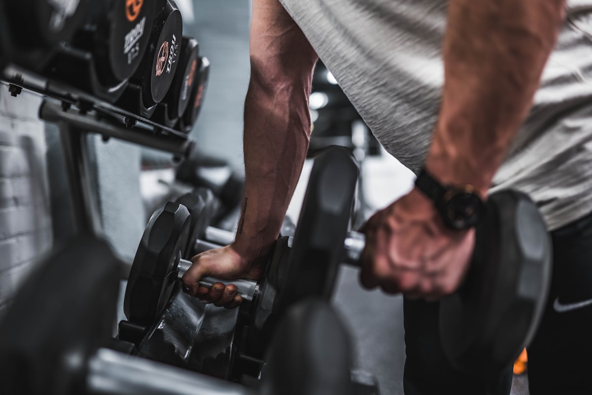 Homem pegando halteres no suporte para treino de musculação
