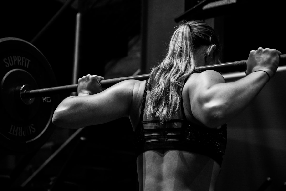 Mulher executando agachamento com barra nas costas na academia